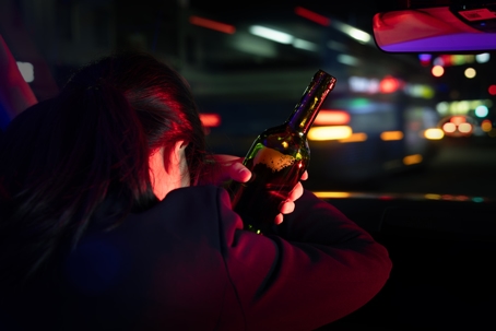 Rear view of a woman driving drunk at night
